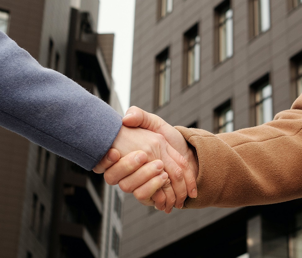 Two people in coats shaking hands outdoors